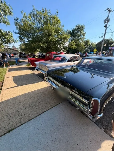 Classic cars lined up along a sunny Flemington street during a car show