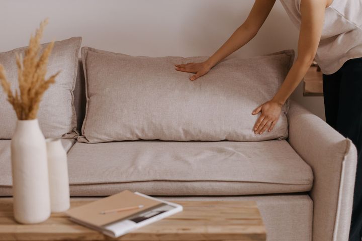 Hands smoothing a cushion on a linen sofa
