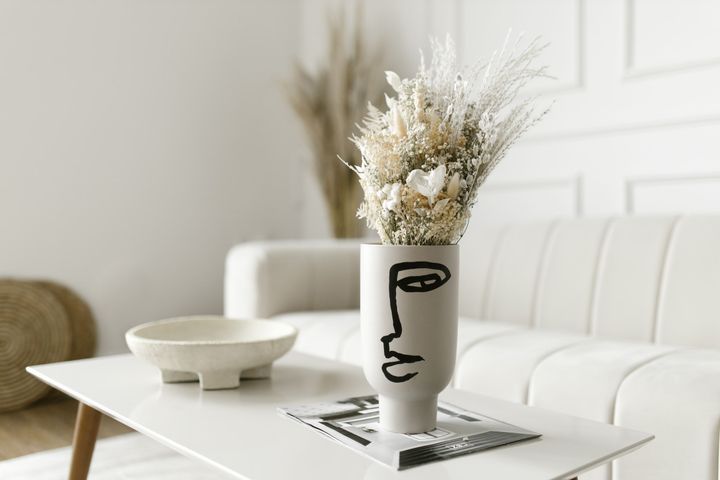 A vase of dried flowers on a white coffee table