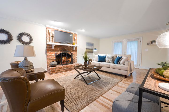 A bright living room with a brick fireplace, a cream sofa and a leather armchair