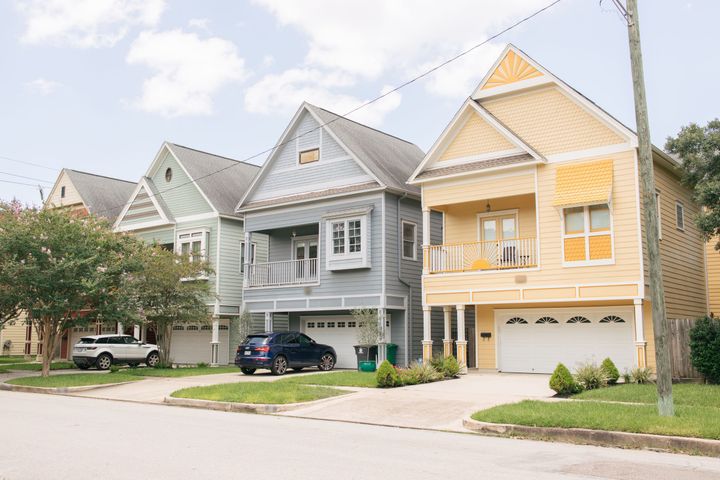 A row of colorful two-story homes with garages on a quiet residential street